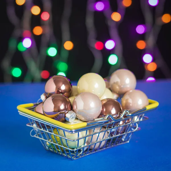형형색색의 조명을 배경으로 철제 바구니에 들어 있는 크리스마스 트리를 위한 공들. — 스톡 사진