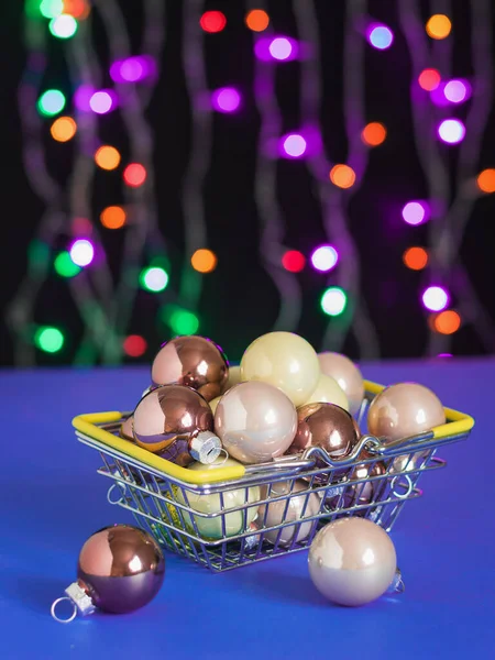 Velký počet vánočních ozdob v kovovém koši na modrém stole. — Stock fotografie