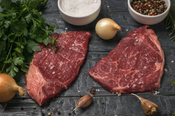 Петрушка, лук, специи и говядина стейки на черном столе. — стоковое фото