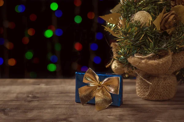 Kék ajándékdoboz sárga masnival a karácsonyfa alatt. Karácsonyi és újévi ünnepségek. — Stock Fotó