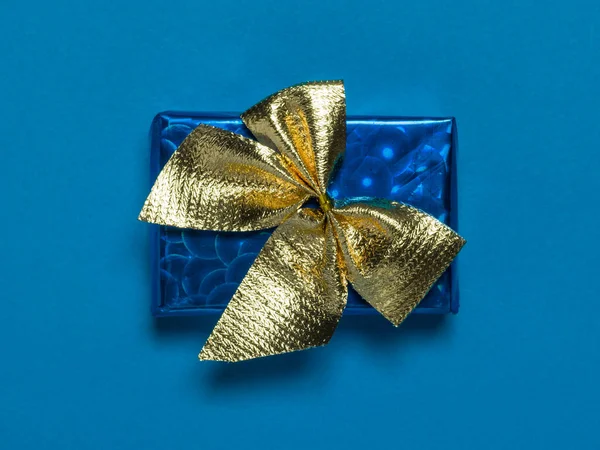 Blauwe doos met een cadeau en een gele strik op een blauwe achtergrond. — Stockfoto