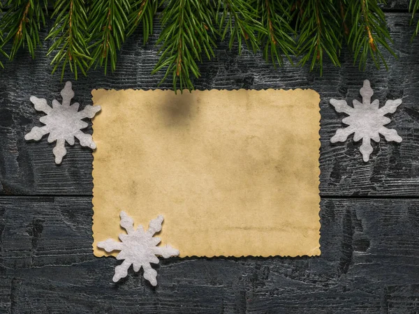List starožitného papíru s papírovými vločkami a jedlovými větvemi na dřevěném pozadí. — Stock fotografie