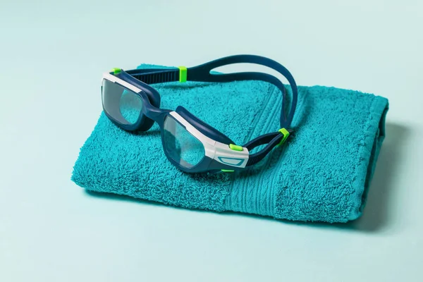 Plavecké brýle na modrém ručníku na modrém pozadí. — Stock fotografie