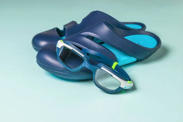 Óculos de proteção e chinelos para a piscina sobre fundo azul. — Fotografia de Stock