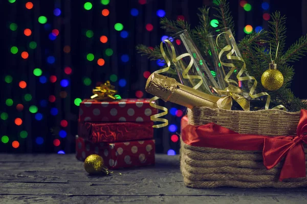 Sweets, gift boxes and champagne on a bokeh background under a Christmas tree. Space for text.