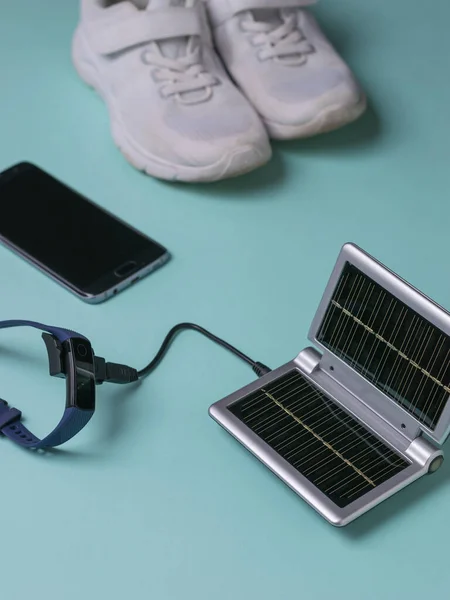 Charging your smart watch from a solar-powered power source during a workout. Use of solar energy.