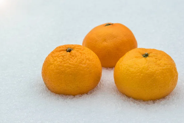 Trzy dojrzałe mandarynki w świeżym śniegu. — Zdjęcie stockowe