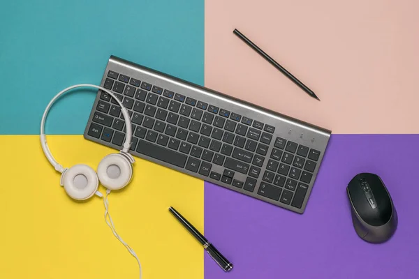Клавіатура, олівці, мишка та навушники на різнокольоровому фоні . — стокове фото