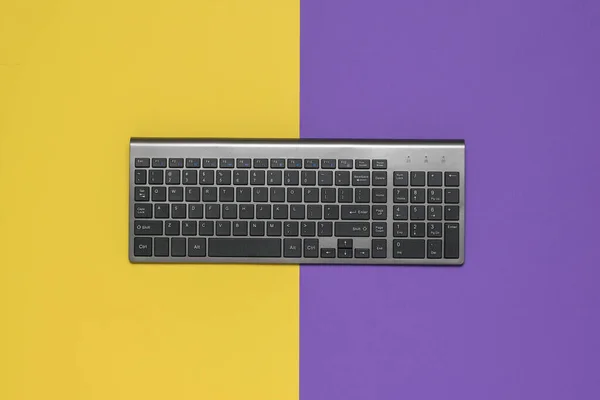 Modernt trådlöst tangentbord på en gul och lila bakgrund. — Stockfoto