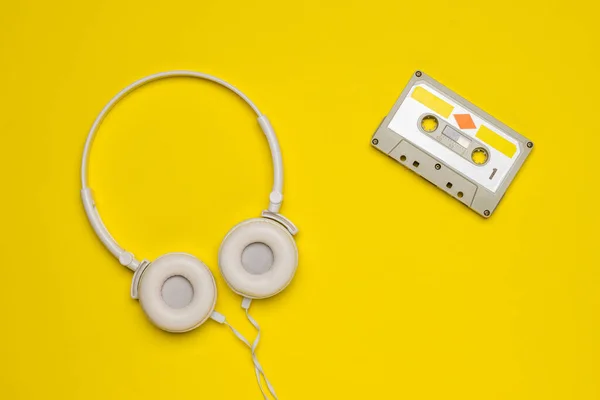 White headphones and a tape recorder on a yellow background.