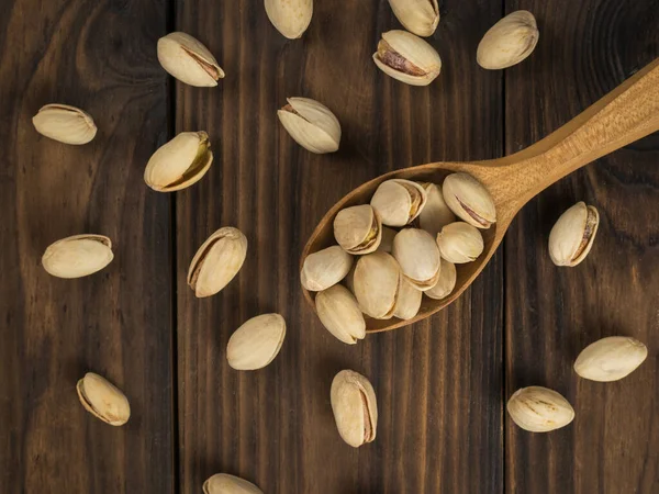 Ahşap bir kaşıkta kavrulmuş fıstık ve masaya saçılmış. Doğal protein ve karbonhidrat kaynağı..