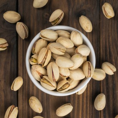 Tahta bir masada beyaz bir kase şam fıstığı..