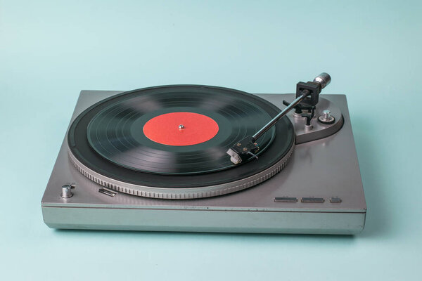 Gray turntable on a blue background. Retro equipment for playing music.