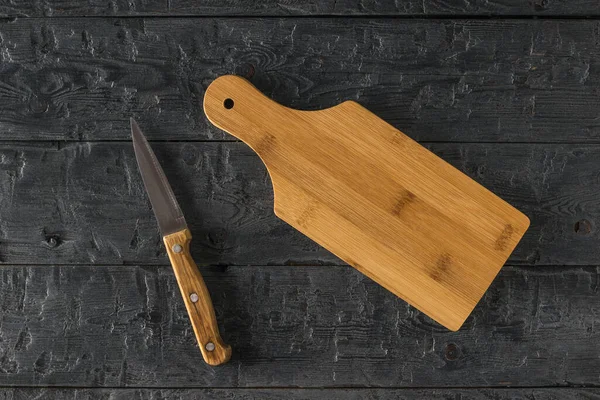 Widok z góry na deskę do krojenia i nóż na drewnianym stole. — Zdjęcie stockowe