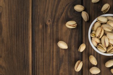 Fıstık dolu seramik kaseli ahşap masa. Doğal protein ve karbonhidrat kaynağı..