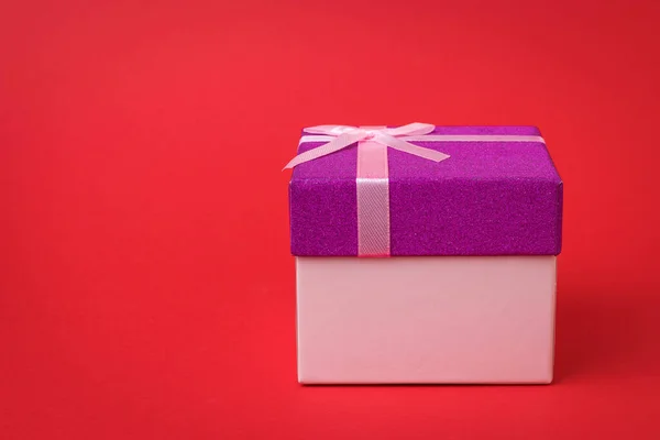 stock image Gift box with pink ribbon on red background. A holiday gift.