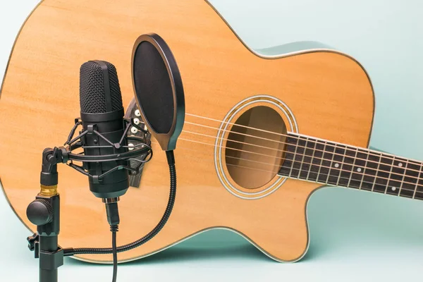 Modern microphone on the background of a six-string guitar. Record and play music.