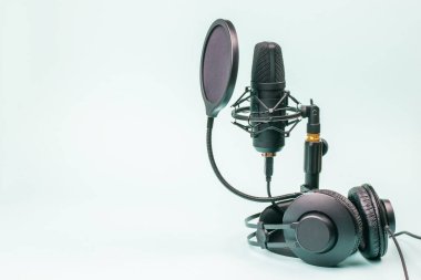 Siyah kulaklıklar ve açık mavi arka planda kabloları olan mikrofon. Ses kayıt ekipmanları.