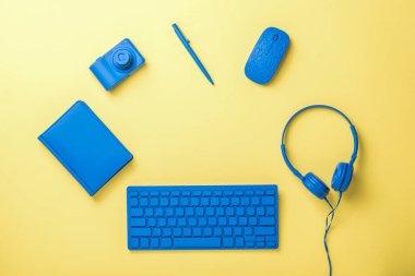 Kablosuz klavye ve fare, kulaklıklar ve sarı arka planda kamera. Ticari ve serbest aksesuarlar için şık aksesuarlar. Düz yatıyordu.