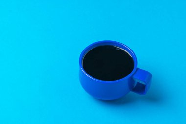 Mavi arka planda bir fincan sade kahve. Popüler canlandırıcı bir içecek..