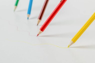 Beyaz arka plana dört renkli kalem çiziyor. Kırtasiye malzemeleri ve okul malzemeleri..