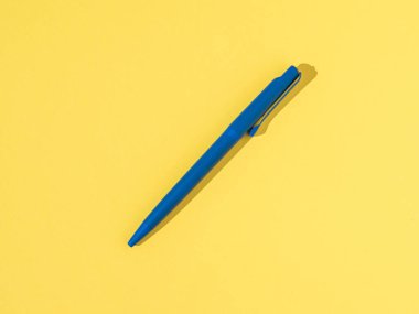 Sarı arka planda parlak ışıkta mavi kalem. Ofis malzemeleri.