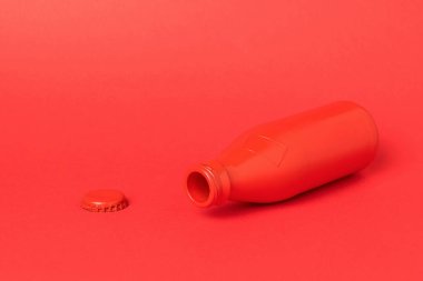 Kırmızı arka planda açık cam kırmızı şişe. Serinletici içecekler için bir kap.