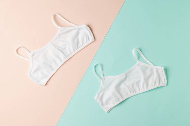 İki renkli arka planda iki basit beyaz sütyen. Kızlar için iç çamaşırı..