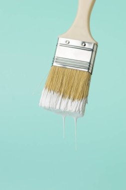 Mavi arka planda damlayan beyaz boya ile fırçala. Resim çalışmalarının yürütülmesi.