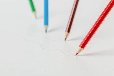 Renkli kalemler beyaz arkaplana renkli çizgiler çiziyor. Kırtasiye malzemeleri ve okul malzemeleri..