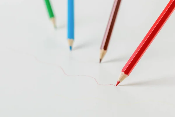 Colored pencils drawing colored lines on a white background. Stationery and school supplies.