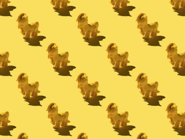 A pattern of yellow pony toys on a yellow background. Monochrome image of a fashionable toy.