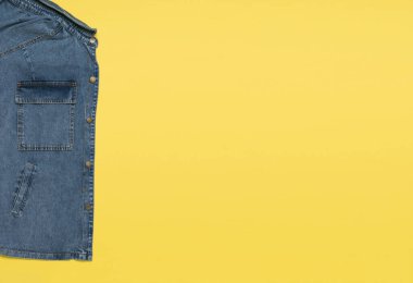 Sarı arka planda mavi kot ceketin bir parçası. Popüler günlük kıyafetler..