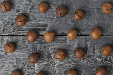 Ahşap bir masada soyulmamış macadamia fındıkları. Süper yemek..