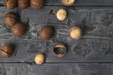 Siyah ahşap bir masada birkaç Macadamia fındığı. Süper yemek..