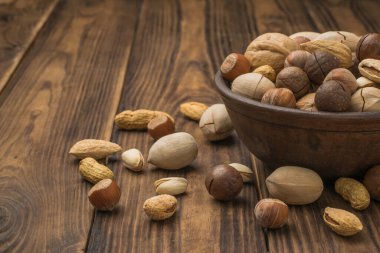 Kahverengi ahşap bir masada farklı fındıklardan oluşan bir kase. Vejetaryen yemeği..