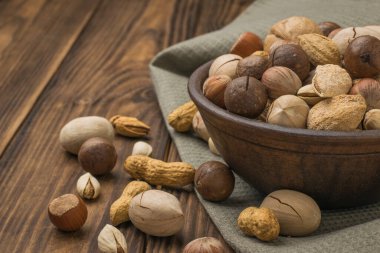 Ahşap bir masanın üzerindeki kumaş parçasında çok sayıda fındık olan bir kase. Vejetaryen yemeği..