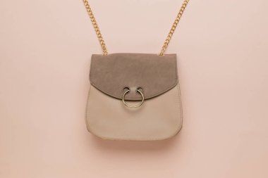 Bej arka planda metal süslemeli şık bej kadın çantası. Modaya uygun bir kadın aksesuarı. Moda kadın aksesuarları. Düz yatıyordu.