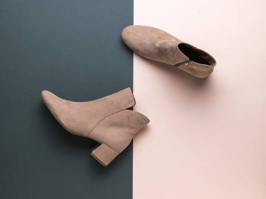 Siyah ve bej arka planda açık renkli süet kadın botları. Yarı sezonluk şık kadın ayakkabıları. Düz yatıyordu.