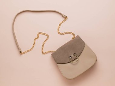 Bej arka planda orijinal bir kayışı olan kadın süet çantası. Modaya uygun bir kadın aksesuarı. Moda kadın aksesuarları. Düz yatıyordu.