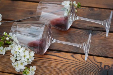 İki kadeh kırmızı şarap ve ahşap masada bir kiraz dalı. Klasik şarap ve kiraz çiçekleri..