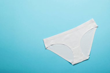 Açık mavi arka planda beyaz pamuklu kadın külotu. İç çamaşırı. Düz yatıyordu.