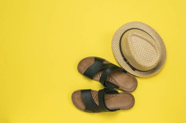 Erkek sandaleti, hindistan cevizi ve sarı arka planda bir şapka. Yaz erkek ayakkabıları..