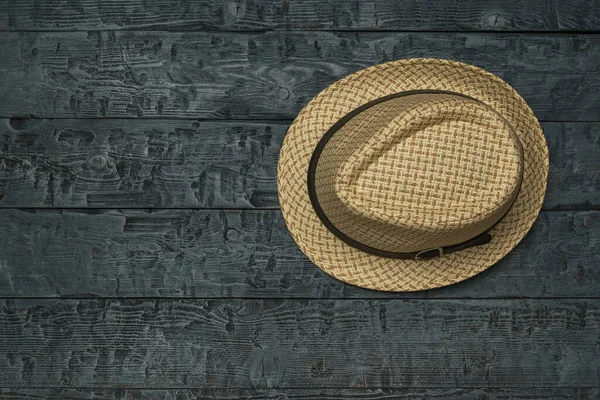 Summer men\'s hat on a black wooden table. Classic men\'s headdress.