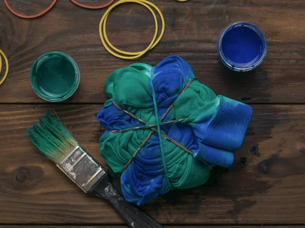 Coloring clothes in the style of tie dye with blue-green color. Staining fabric in tie dye style.