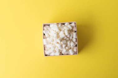 Sarı arka planda küçük bir şekerleme kutusu. Tatlı bir ikram. Düz yatıyordu.