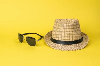 Sarı arka planda erkek şapkası ve güneş gözlüğü. Erkekler için aksesuarlar.