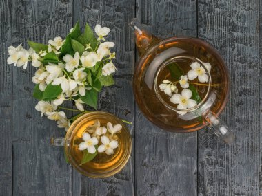 Bir bardak çaydanlık ve bir bardak yasemin çayı, ahşap zeminde. Sağlığın için iyi olan canlandırıcı bir içecek..
