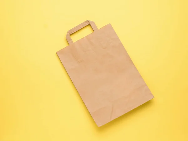 黄色の背景にハンドル付きの古典的な紙袋 — ストック写真
