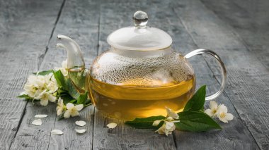 Yasemin çiçekleriyle dolu tıbbi çayla dolu cam bir çaydanlık. Sağlığın için iyi olan canlandırıcı bir içecek..